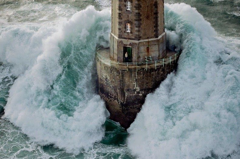 Une immense vague frappe un phare isolé au cœur de la tempête